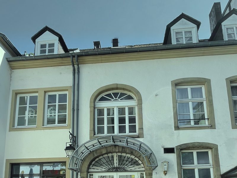 Hausfassade am Postgäßchen mit Gauben, Sprossenfenstern und dem gläsernen Vordach über dem Eingang